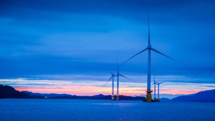 The Hywind floating wind farm at sunset looking across a calm sea.